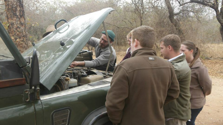 Safari guide students working on a vehicle